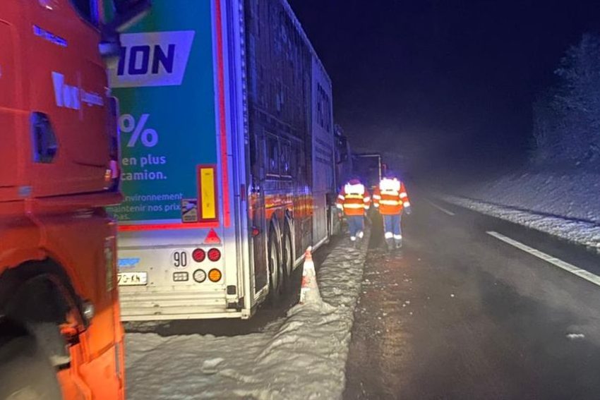 Deux secouristes de la Protection Civile Normandie Seine marchent à côté de camions dans la nuit et sous la neige.