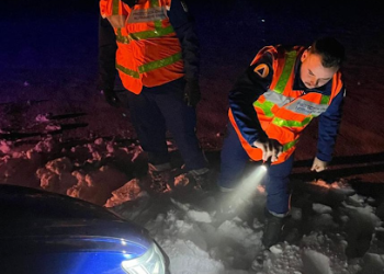 Deux secouristes de la Protection Civile Normandie Seine éclairent une voiture avec une lampe torche pour vérifier s'il y a quelqu'un à l'intérieur.